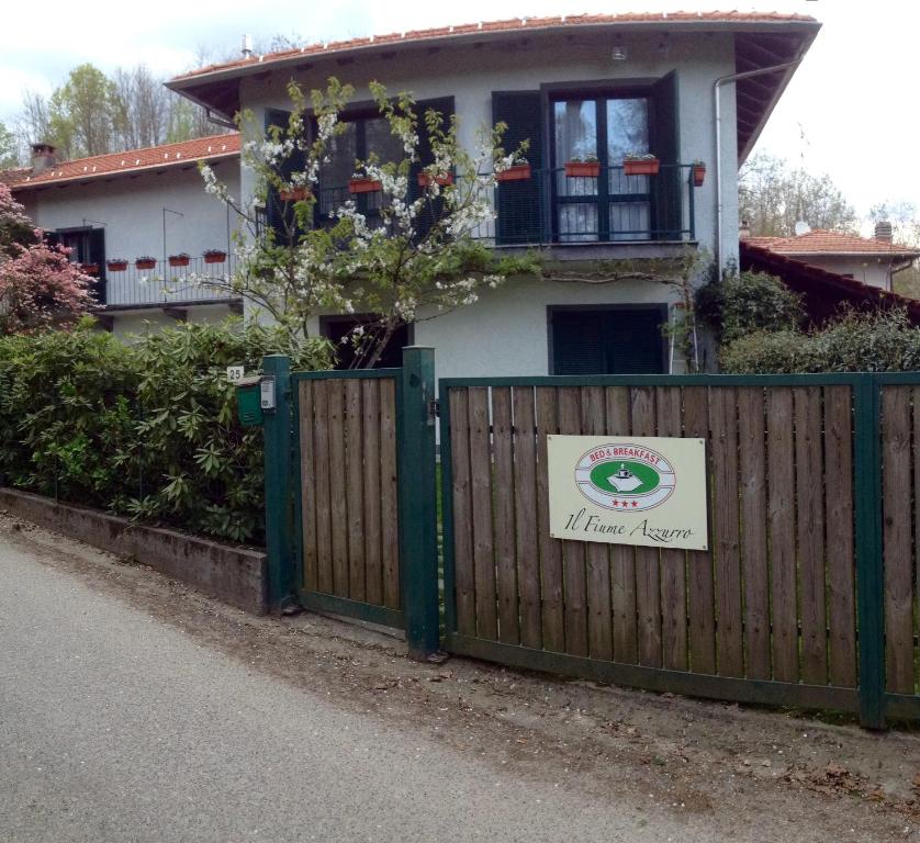 una casa con una recinzione con un cartello sopra di Il Fiume Azzurro Home B&B a Castelletto sopra Ticino