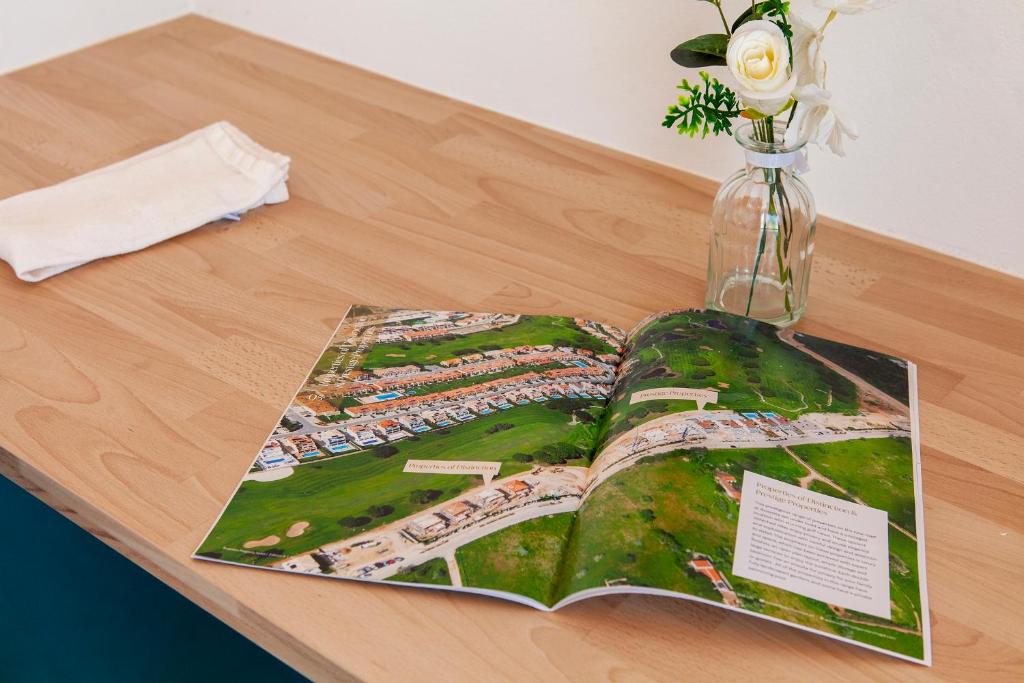 a book on a table with a vase with flowers at Alegria's House in Odiáxere