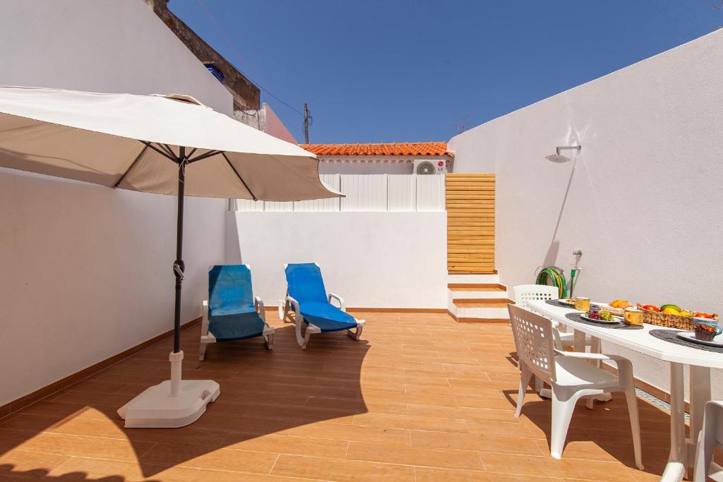 a patio with a table and chairs and an umbrella at Alegria's House in Odiáxere