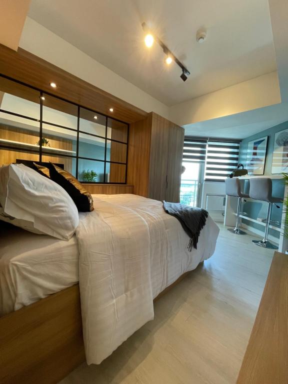 a bedroom with a large white bed and a kitchen at KRYSTL KRIB Azure North in San Fernando