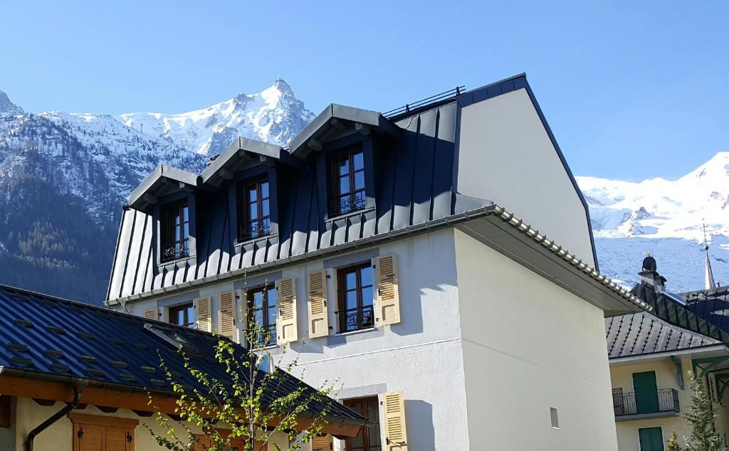 a white building with mountains in the background at Hotel Du Clocher in Chamonix
