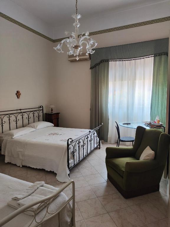 a bedroom with a bed and a chair and a table at B&B Betania in Riposto