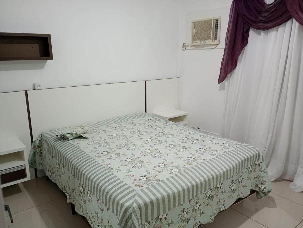 1 dormitorio con 1 cama con manta verde y blanca en Apartamento Quadra Mar Meia Praia, en Itapema