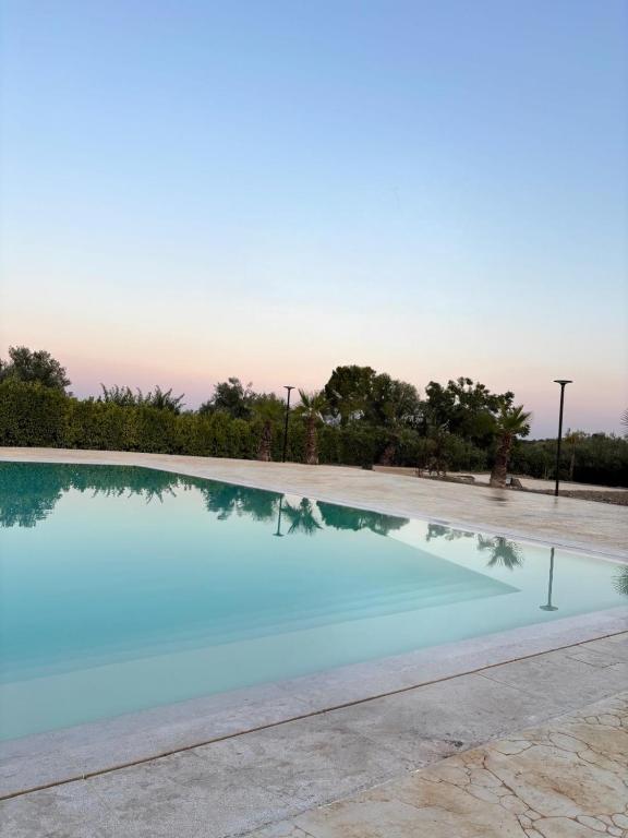 a large swimming pool with a sunset in the background at VILLA BORGHESE in Racalmuto