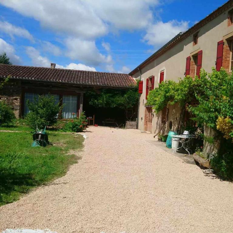 a driveway leading to a building with red windows at Maison d'hôtes la Passemarié in Andouque