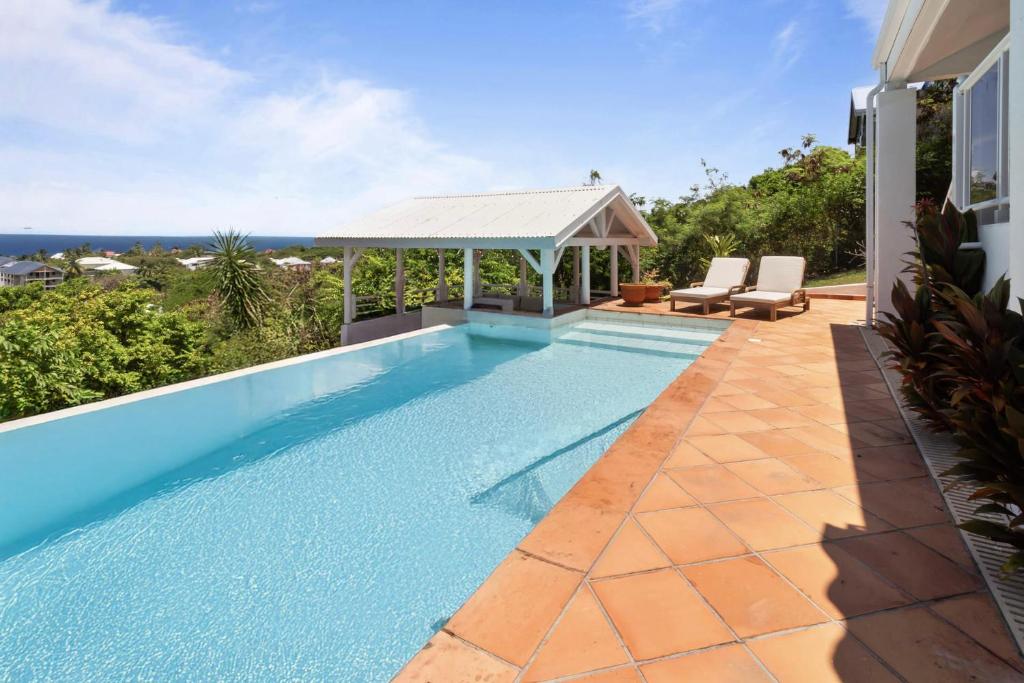a swimming pool with a gazebo next to a house at Villa Maravistah in Saint-François