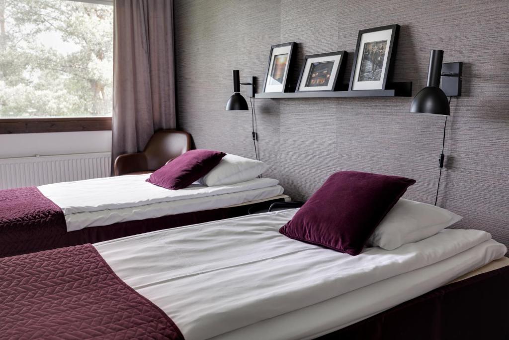 2 bedden in een hotelkamer met paarse kussens bij Hotel Käenpesä in Ylivieska