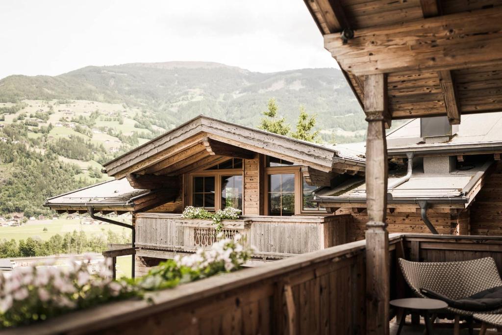 a wooden house with a balcony with a table and chairs at Das Kaltenbach - ApartHotel in Kaltenbach