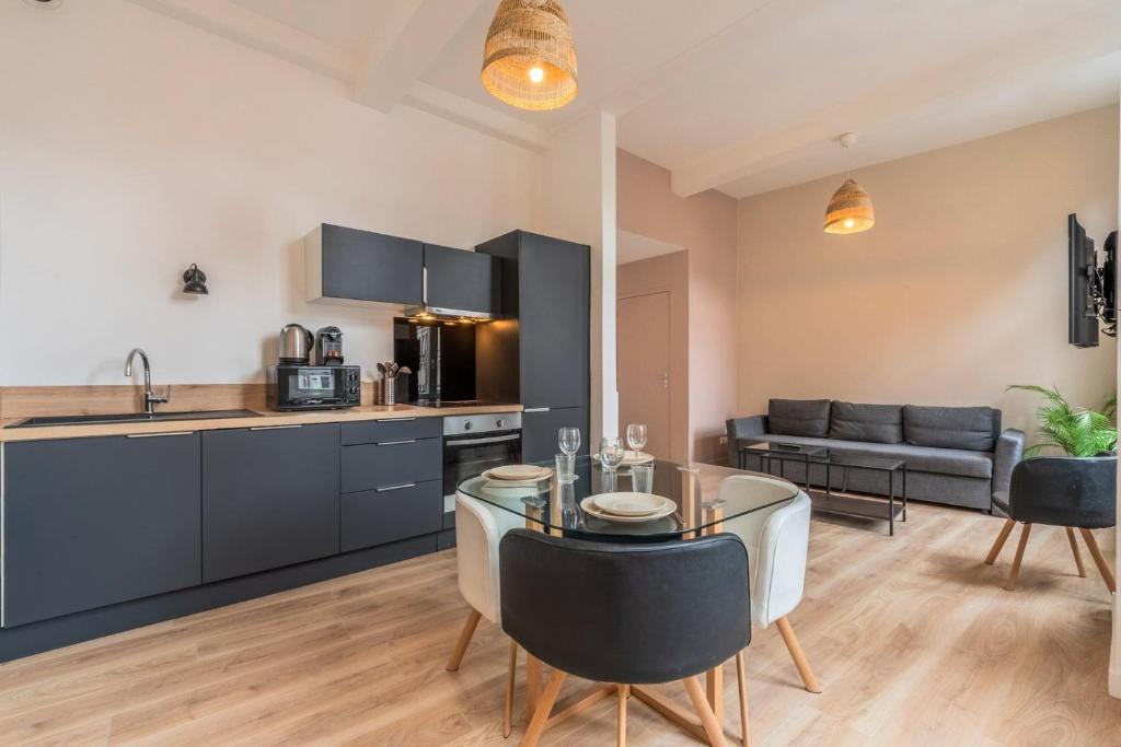 Il dispose d'une cuisine et d'un salon avec une table et des chaises en verre. dans l'établissement Lille Gares - 50m2 apartment!, à Lille