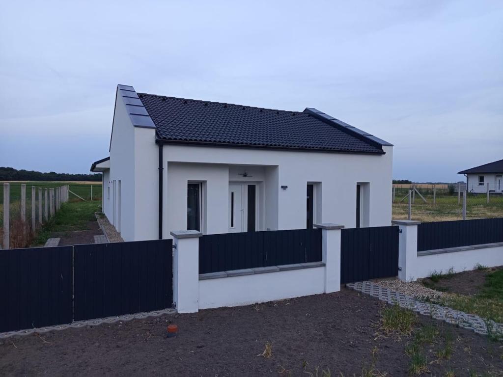 a small white house with a black fence at Áporka vendégház 