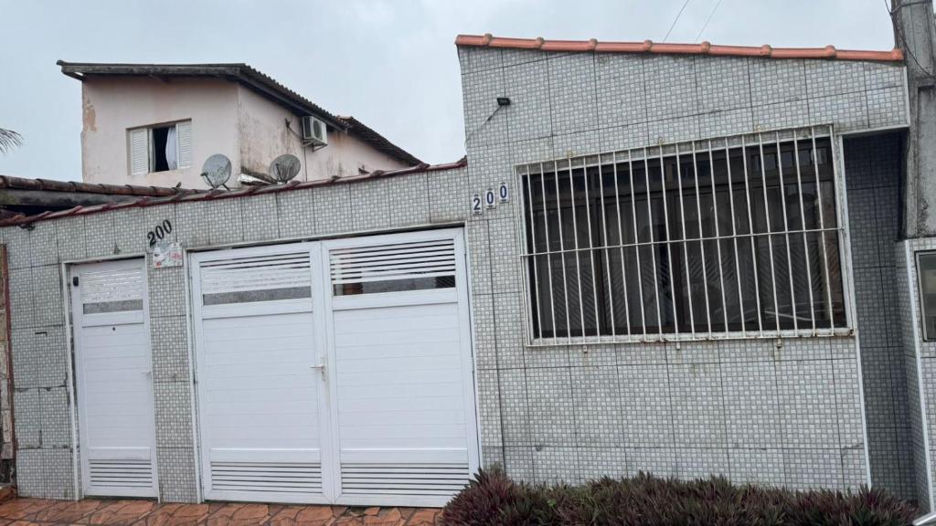 un edificio de ladrillo con dos puertas blancas de garaje en Pousada Flores do Campo Ita, en Itanhaém
