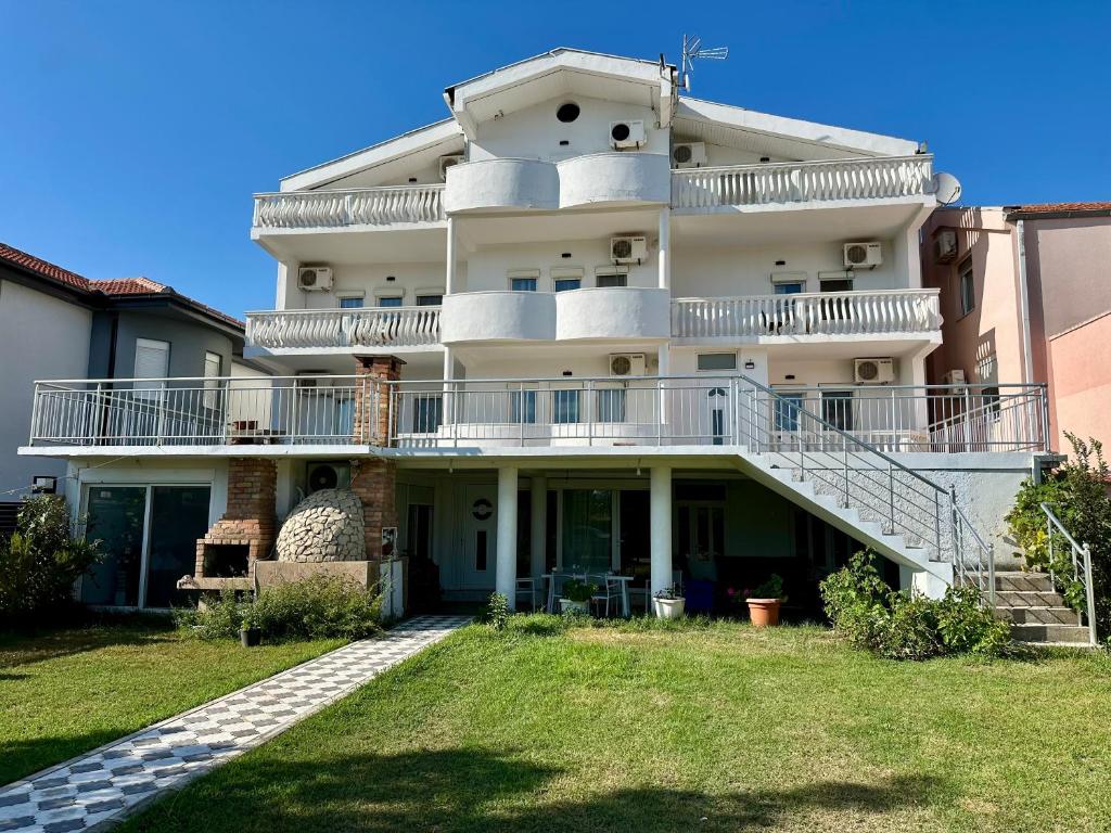 a large white building with a balcony and grass at Villa Paris in Donji Štoj