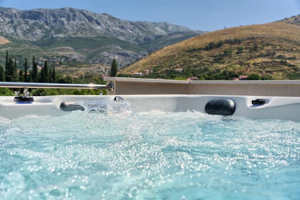 a bath tub filled with water with mountains in the background at Relax penthouse private jacuzzi Split area in Žrnovnica