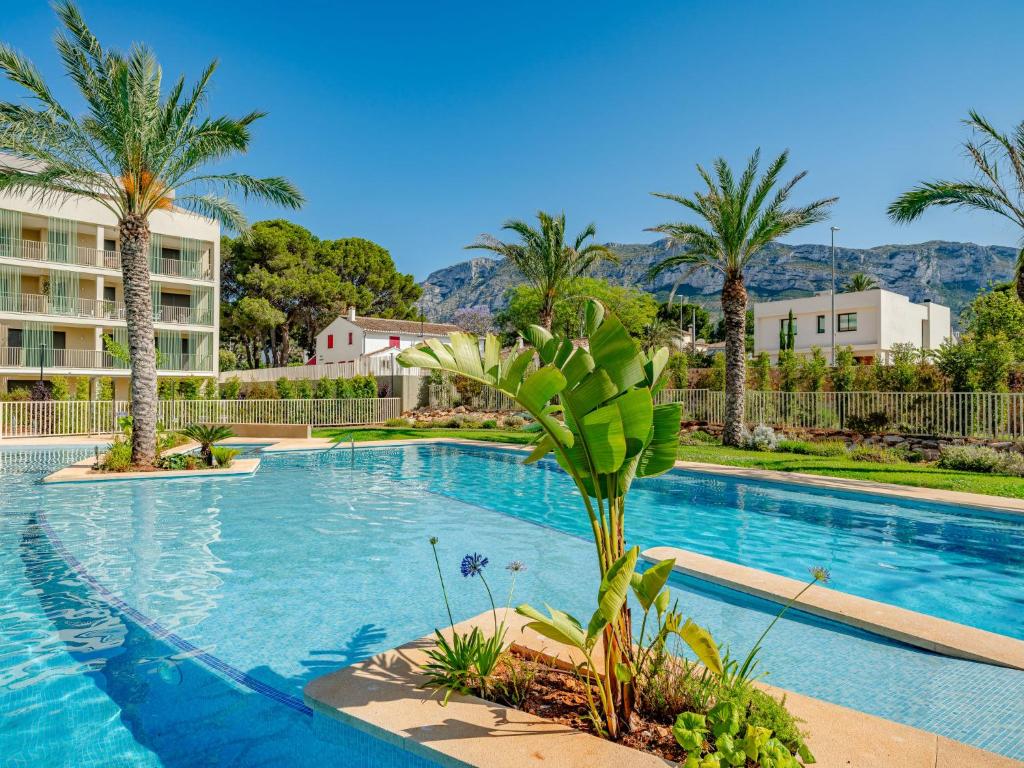 a swimming pool with palm trees and a building at Holiday Home Nerva by Interhome in Denia
