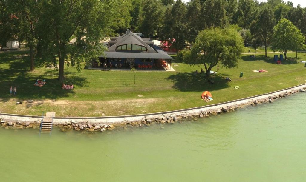 uma pessoa sentada na relva ao lado de um lago em Szines Panoráma Apartman em Balatonlelle