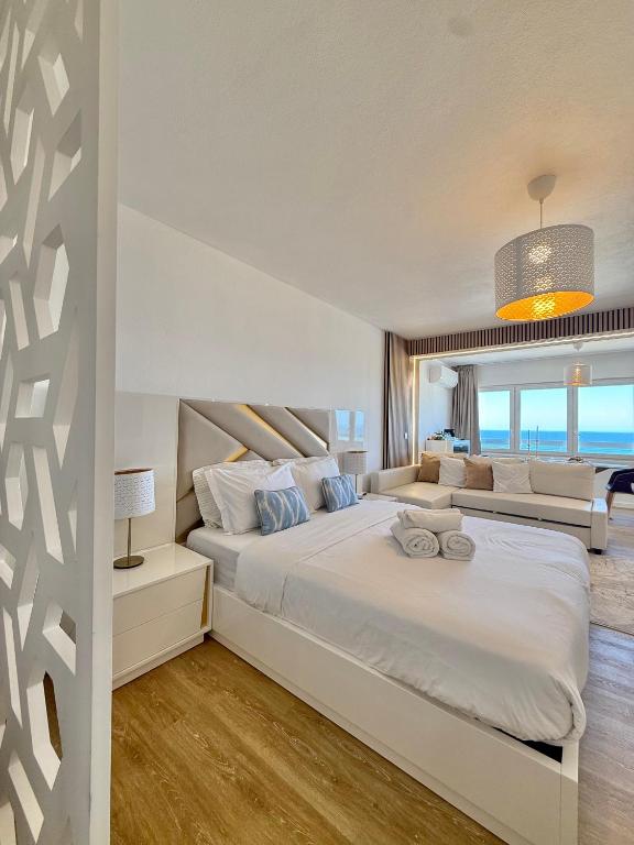 a bedroom with a large white bed and a couch at The View Costa Caparica in Costa da Caparica
