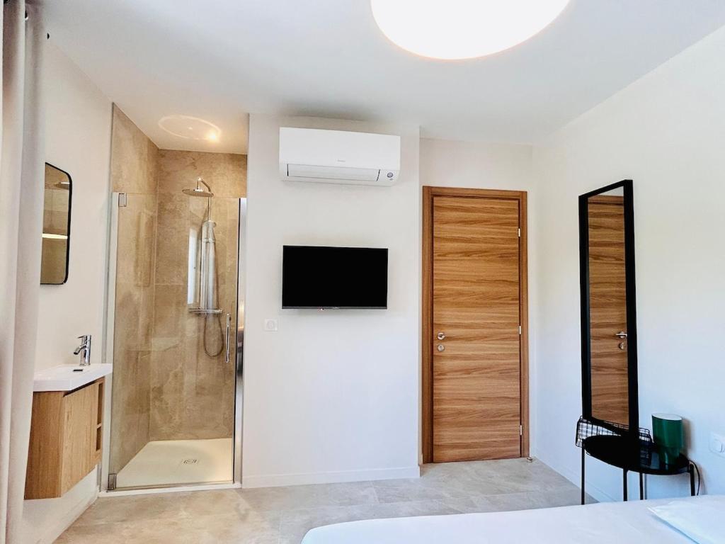 Coliving - Private Shower - Bfast & Terrace Dining في كاجنيس سور مير: غرفة نوم مع دش وتلفزيون على الحائط