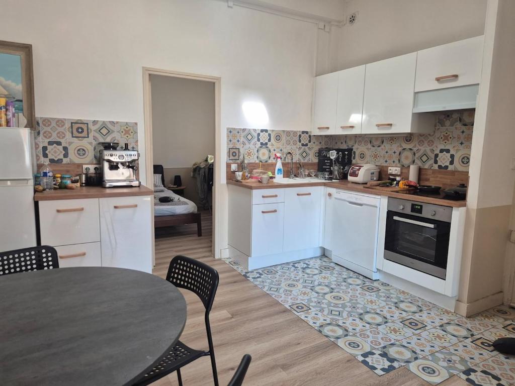 パラヴァ・レ・フロにあるBel appart rénové centre villageの白いキャビネットとテーブルと椅子のあるキッチン