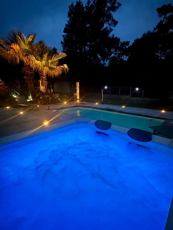 une piscine la nuit avec des lumières bleues dans l'établissement Le Chai de l'Océan - Villa Soulacaise plage à 100m Piscine Jardin 1400m2, à Soulac-sur-Mer