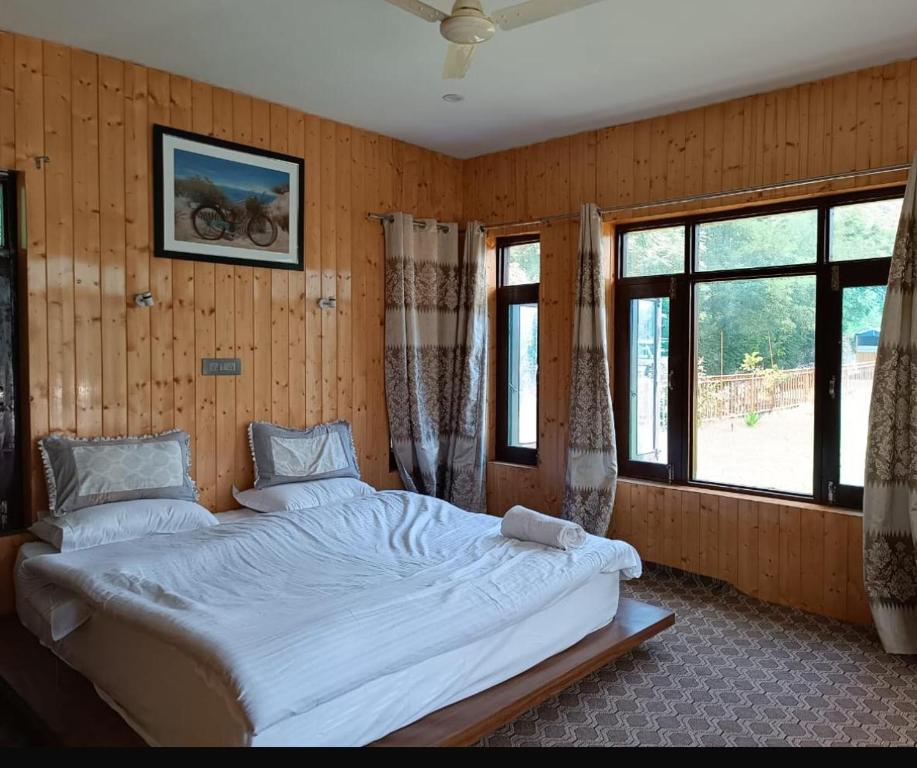 a bedroom with a large white bed in a room with windows at ROYALE PEAKS villa sonamarg Rd 