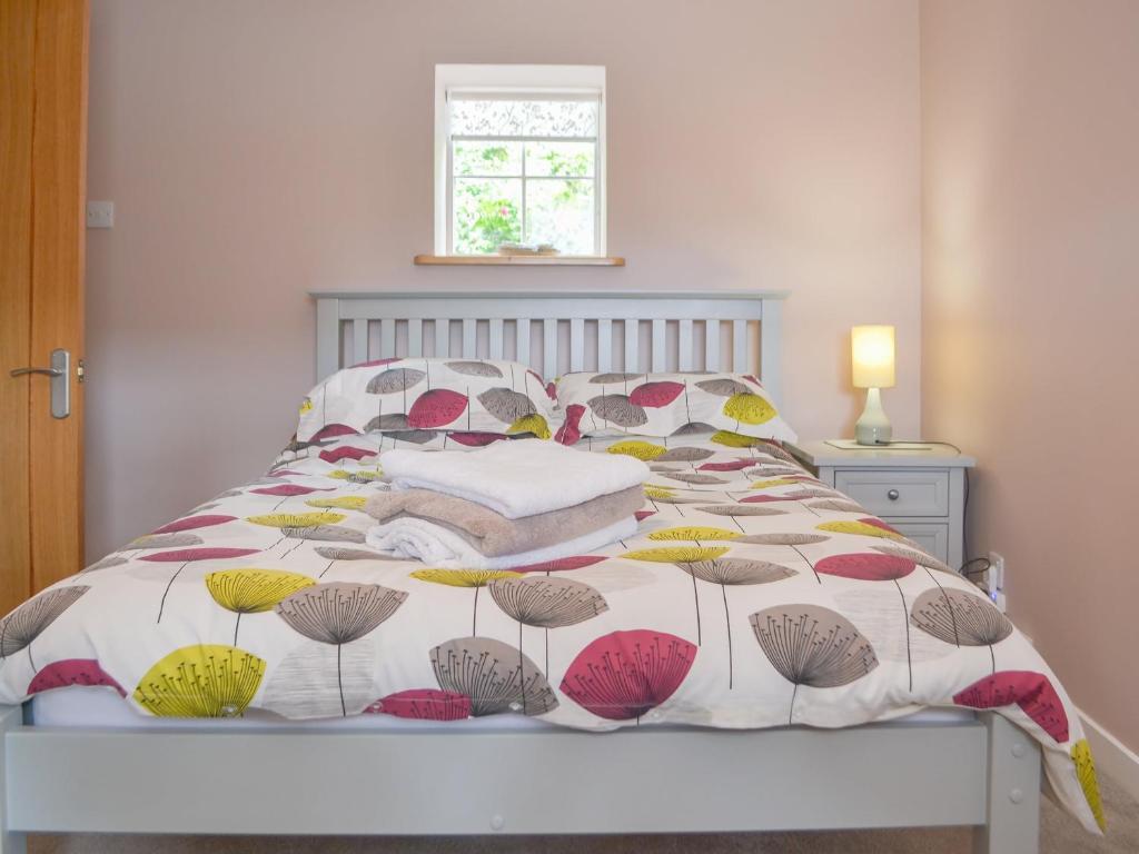 un letto con un piumone colorato e cuscini sopra di Mansefield Cottage a Boyndie