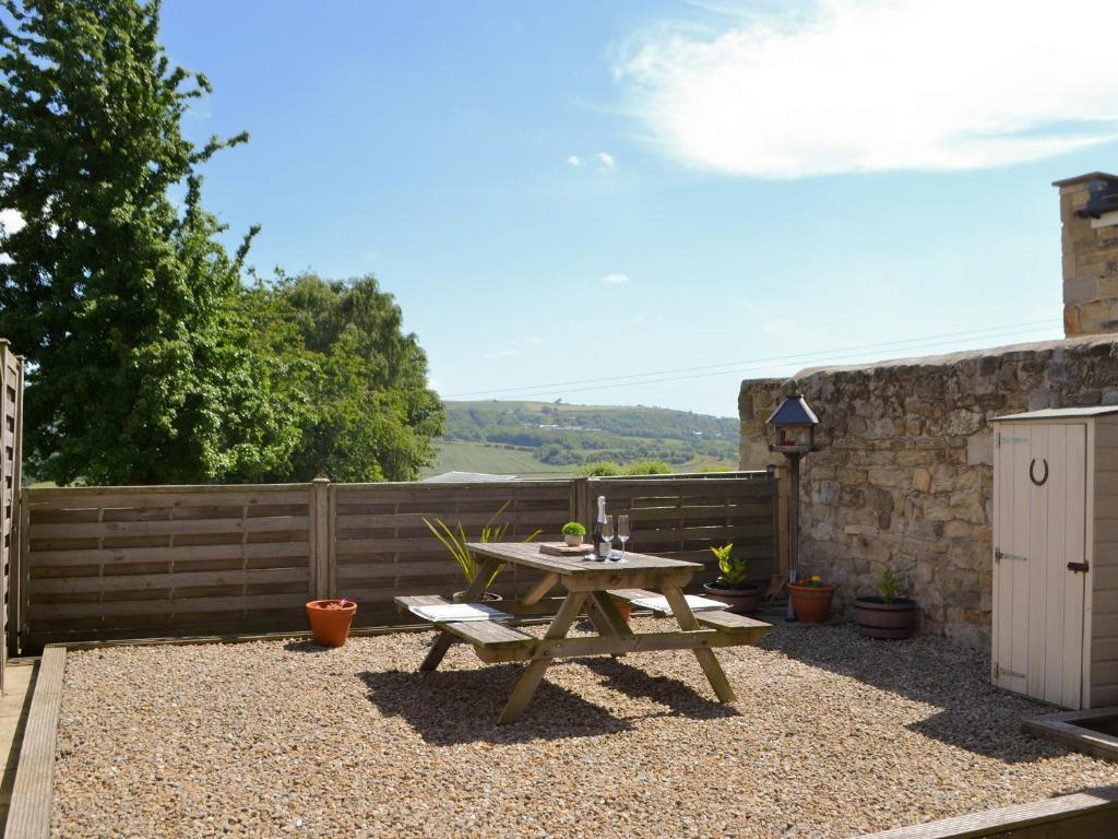 a wooden picnic table in a yard with a fence at Dolly's Cottage in Ovingham