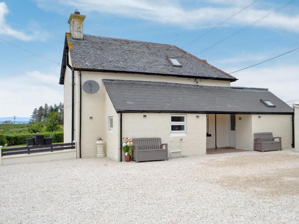 a white building with two chairs in front of it at Cuillin View Apartment - Uk12529 in Arisaig