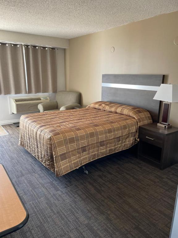 a hotel room with a bed and a chair at Hilltop Motor Inn in Elk Point