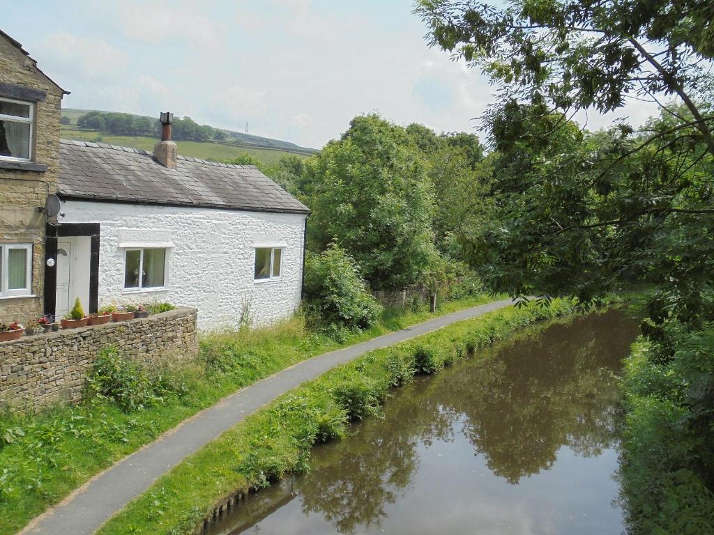 ein Haus und eine Straße neben einem Fluss in der Unterkunft The White Cottage in Furness Vale