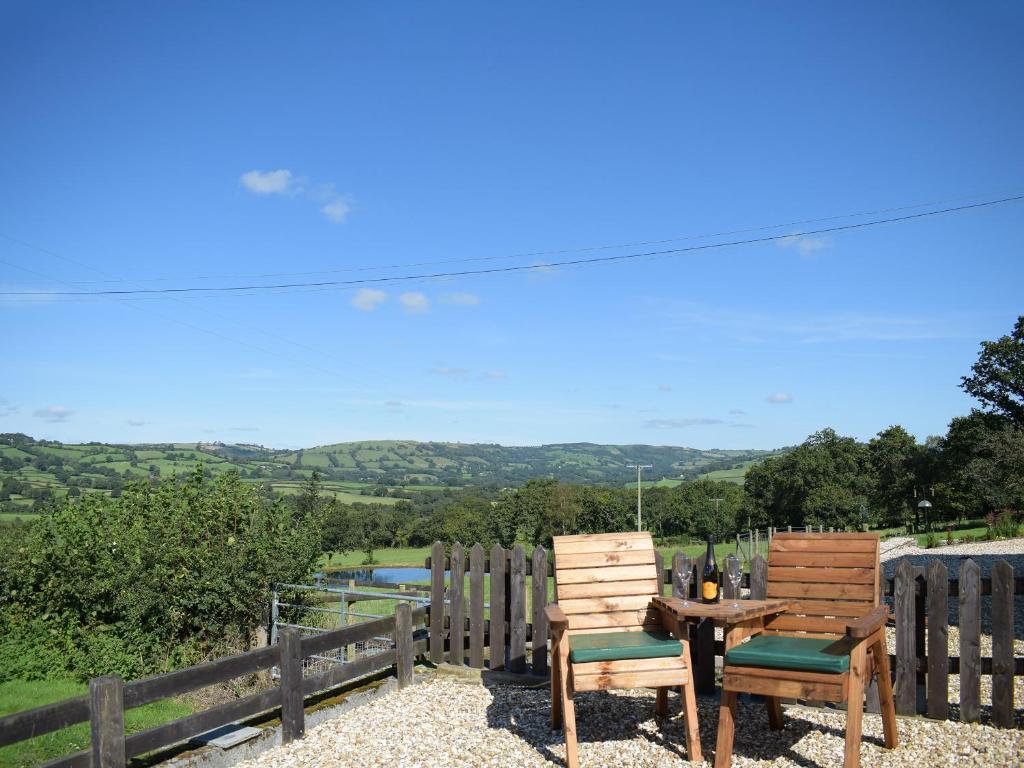 2 Holzstühle und ein Tisch mit Aussicht in der Unterkunft Dairy Cottage in Talley