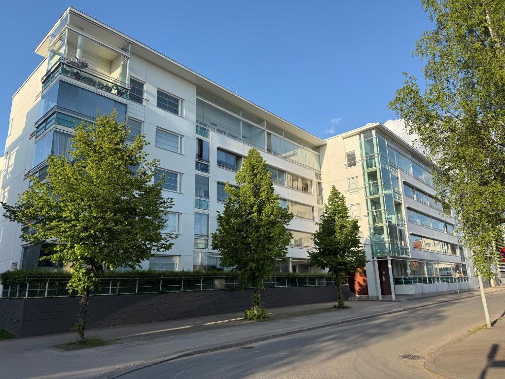 a white building with trees in front of it at Cozy Central Apartment with Sauna in Oulu