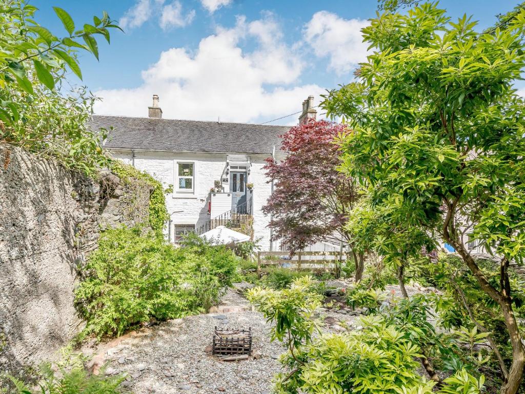 an exterior view of a white house with trees at Pier Haven - Cottage in Blairmore