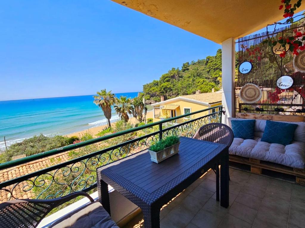 a balcony with a table and chairs and the beach at Corfu Glyfada Menigos Resort 25 in Glyfada