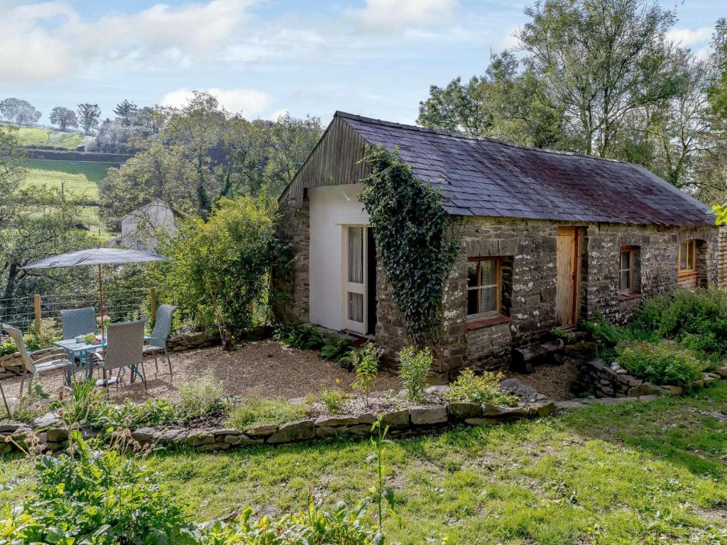 a stone cottage in the garden with a table and chairs at 1 bed in Llandysul 85671 in Rhyd Owen
