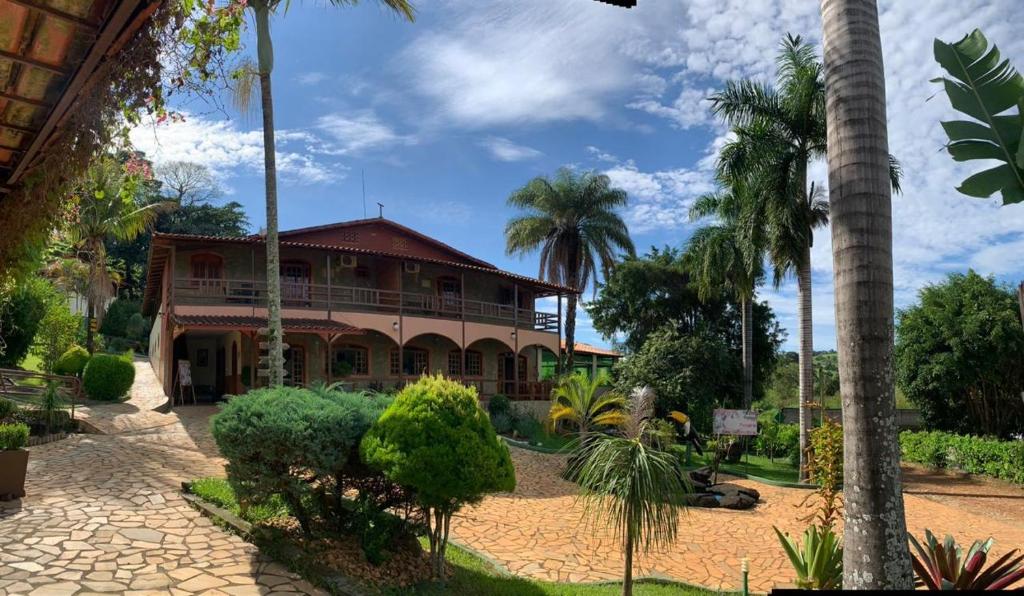 a large house with palm trees in front of it at Hotel Fazenda Tucano in Capim Branco