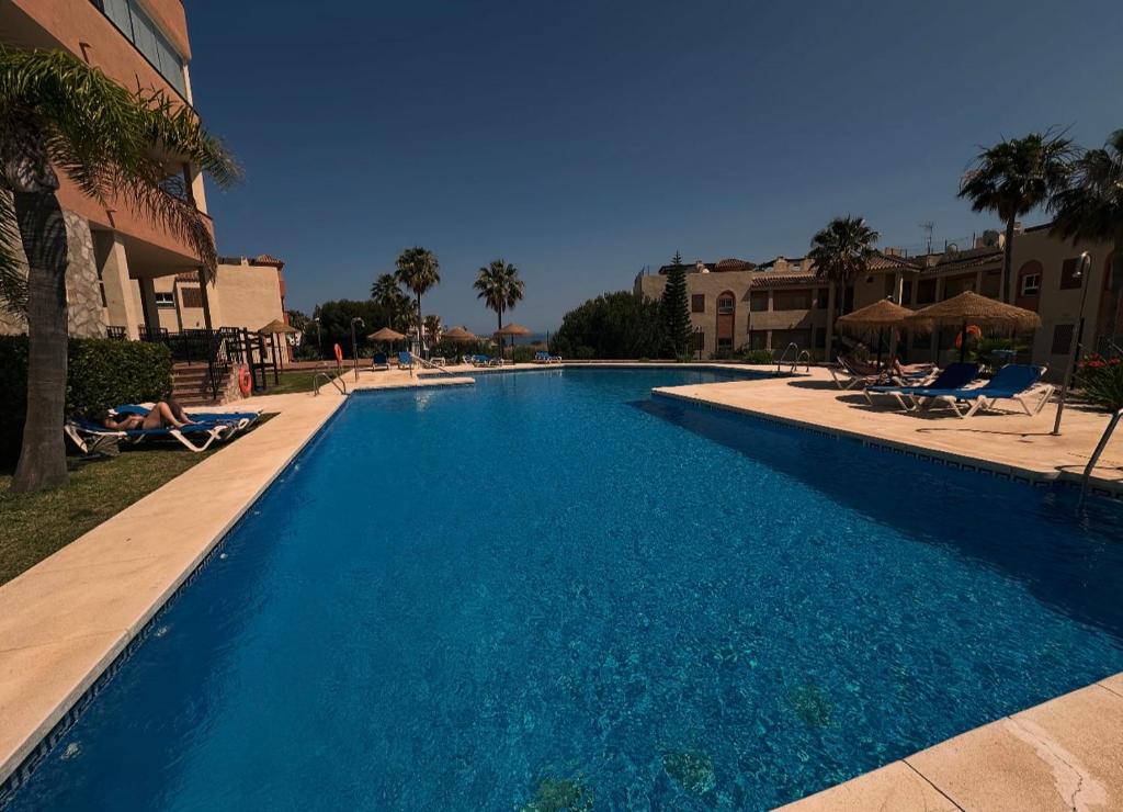 a large blue swimming pool next to a building at Casa Ricardo Penthouse in Sitio de Calahonda