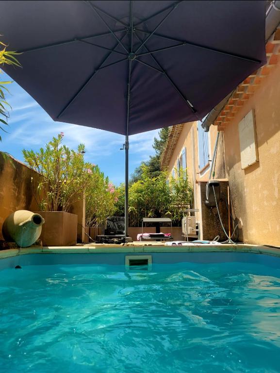un grand parasol bleu posé au-dessus d'une piscine dans l'établissement Logement indépendant Au Bonheur cuisine piscine clim proche centre village #dentelles Montmirrail, à Beaumes-de-Venise