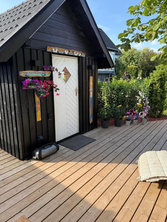 a black shed with a white door on a deck at Happy Mermaid Garden Cabin in Aalborg