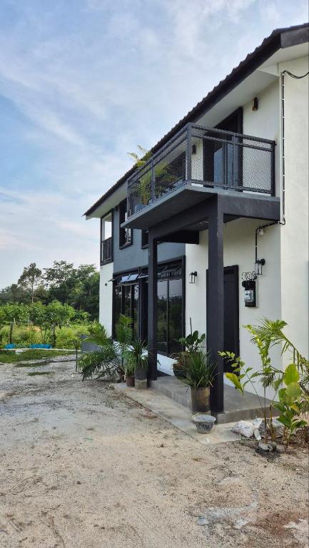a white house with a balcony and some plants at Villa Aisya in Kampung Padang Masirat