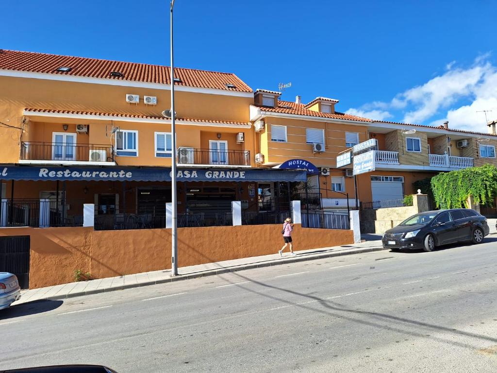 a woman walking down a street in front of a building at Hostal Casa Grande in Baza
