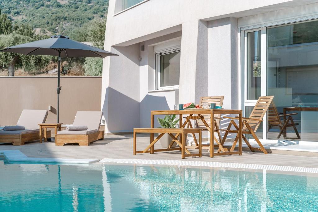 a patio with a table and chairs next to a pool at Tortuga Luxury Villas Sivota in Syvota