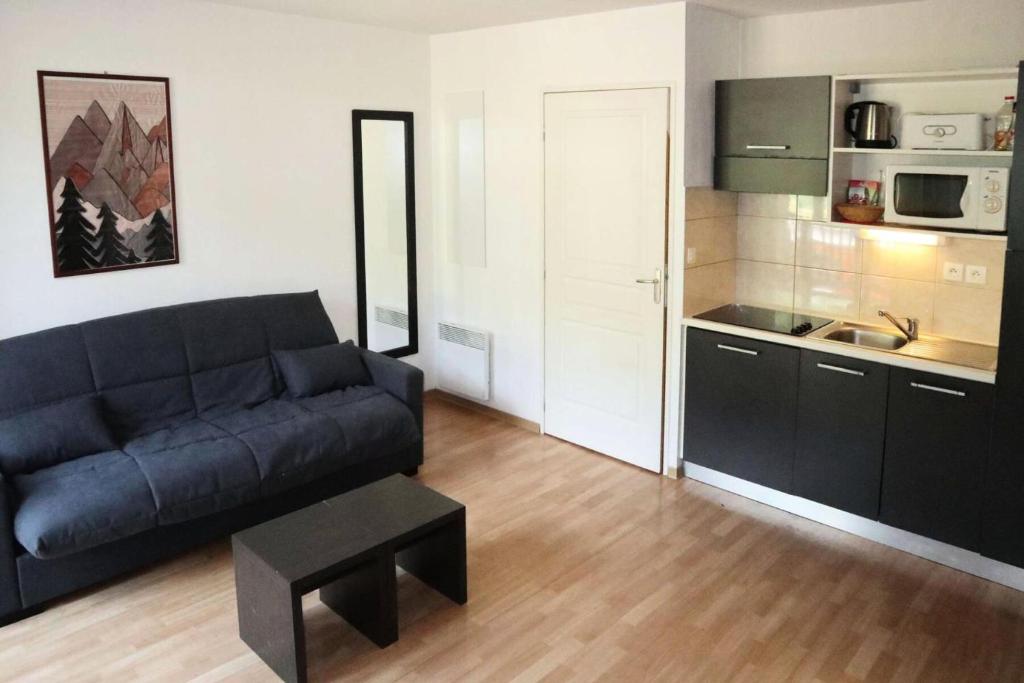 un salon avec un canapé noir et une cuisine dans l'établissement Résidence Les Terrasses Du Soleil D'or - 1107 TERRASSES DU SOLEIL D'OR, LES ORRES 1800 MAE-6774, aux Orres