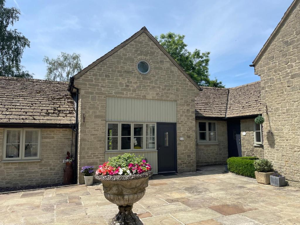 ein Backsteinhaus mit einem Blumentopf davor in der Unterkunft Sherbourne Cottage, Seven Springs Cottages in Cheltenham
