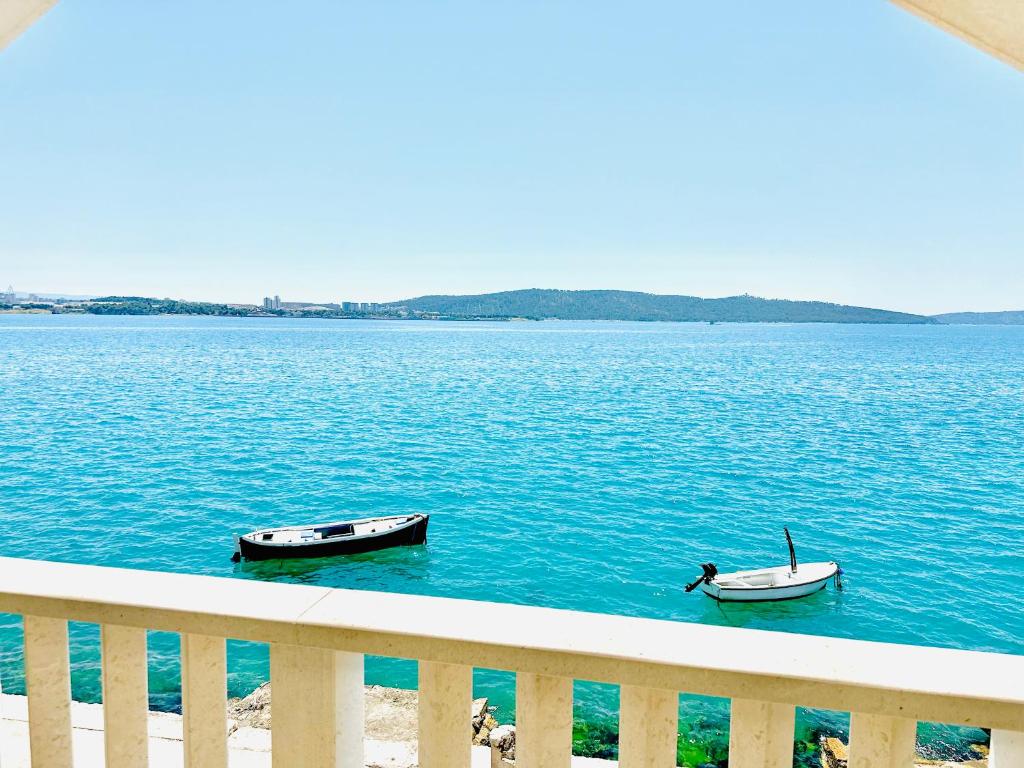 two boats in the water next to a fence at Stella Apartments in Kaštela
