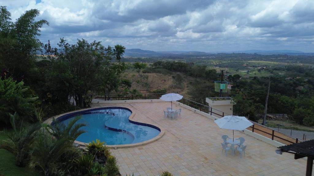 a swimming pool with umbrellas and tables and chairs at Flat 505 Condomínio Topo da Montanha in Chã Grande