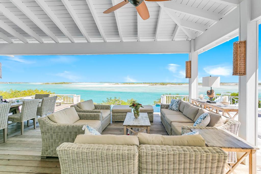 a patio with couches and tables and the ocean at Bahari House - Luxury Oceanfront Villa with Spectacular View, Pool, Spa and Dock in Hartswell