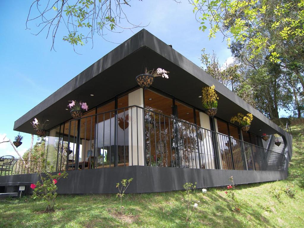 Una casa negra con flores en la parte delantera. en Cabañas el Retorno, en Guatapé