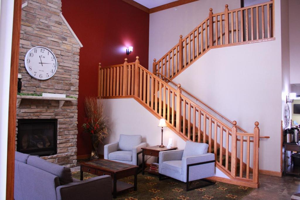 un salon avec un escalier et une horloge dans l'établissement Canby Inn and Suites, à Canby