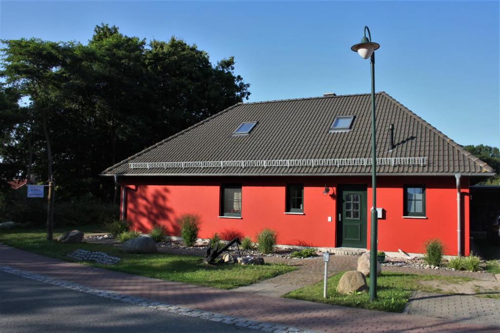 a red house with a black roof on a street at Ferienhaus Am Pappelwald in Glowe