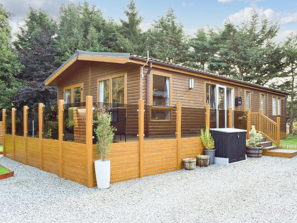 Cabaña de madera con valla y macetas en Riverside Lodge, en Auchterarder